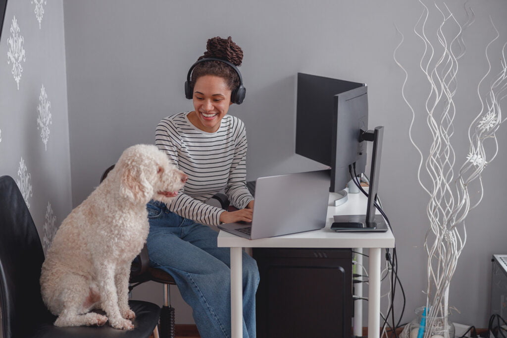 Arbetande kvinna vid skrivbord med sin hund